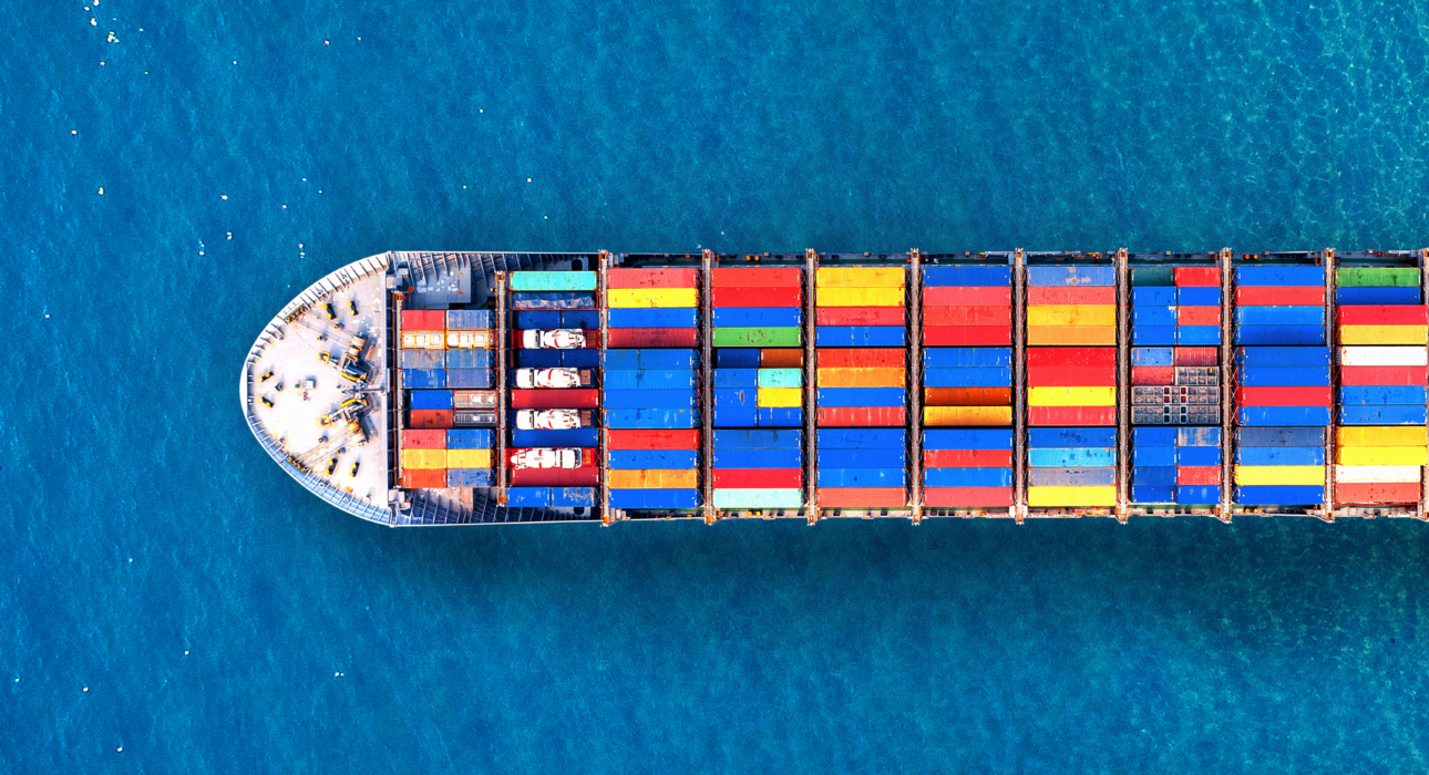 Aerial view of a large container ship carrying colorful containers across a deep blue sea.