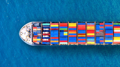 Luchtfoto van een groot containerschip met kleurrijke containers op een diepblauwe zee.